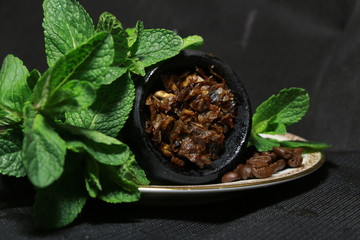 bowl with tobacco for hookah. fruits on a black background. smoke hookah