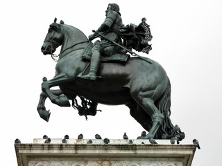 Fototapeta na wymiar Equestrian statue in profile on white background. Pigeons sit on the statue. Spain, Madrid.
