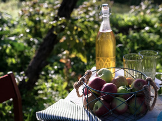 Apple juice in glass bottle and apples fruits in autumn