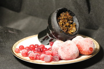 bowl with tobacco for hookah. fruits on a black background. smoking hookah
