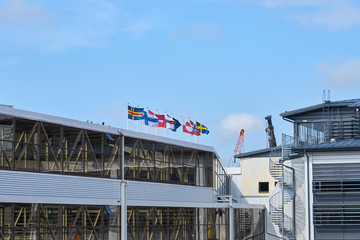 Flags of Nordic Countries and territories against a blue cloudy sky. © Arthur