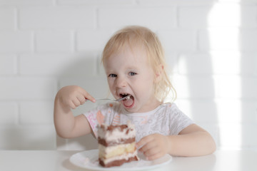 baby girl eating cake sitting at the table