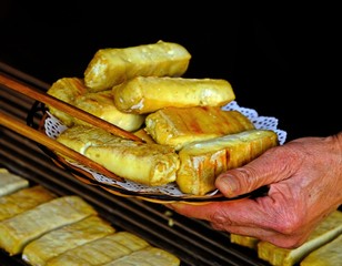 Shot of Chinese grilled tofu being moved from stove to the dish using chopsticks.