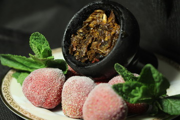 bowl with tobacco for hookah. berries on a black background