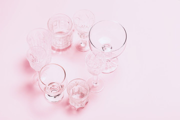 Many empty glasses on pink background. Top view, flat lay.