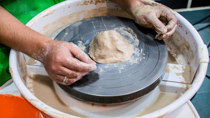 A raw clay pot in the hands of a potter. Workshop in the pottery workshop