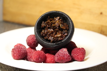 Fototapeta na wymiar bowl with tobacco for hookah. berries on a black background