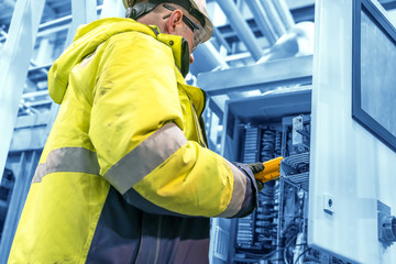 an technical engineer performs a measurement in a control cabinet