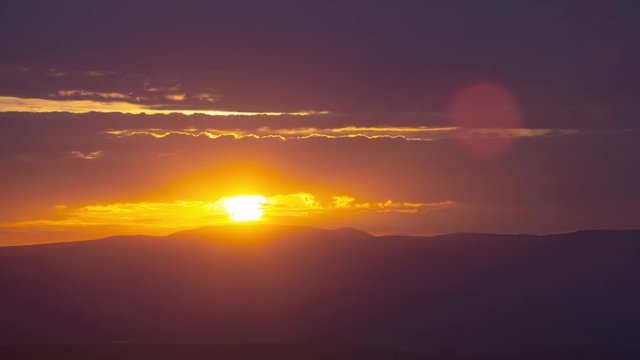 Beautiful orange dawn with the sun rising behind active cumulus clouds. Timelapse zoom in.
