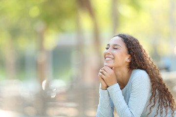 Happy mixed-race woman meditating in a park