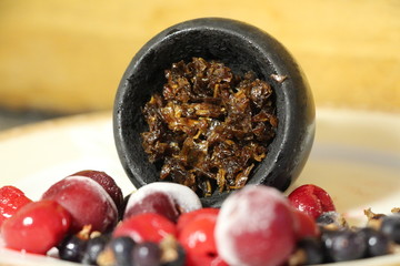 bowl with tobacco for hookah. berries on a black background