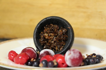 bowl with tobacco for hookah. fruits on a black background