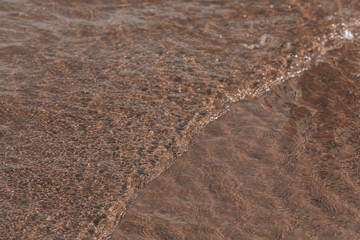 Clear water on the beach. Tide on a sandy beach in summer