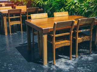 Fototapeta na wymiar Wooden dining table set near the green garden.