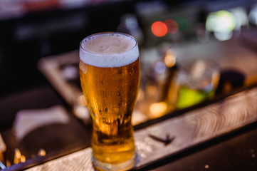 Glass of light beer on a bar.