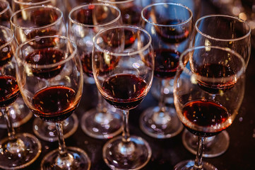 Many glasses of red wine in a row on bar counter.