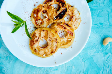 Grilled apples with cinamon on white plate on blue background. Grilled dessert. Barbecue fruit. Copy space. Healthy food. Vegan food.