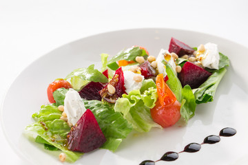Salad with roasted beetroot, tomato, soft goat cheese isolated on white background