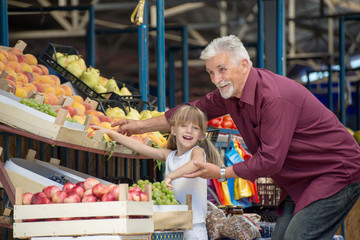 Granddaughter and grandfather  buying  at the green market