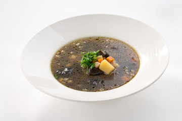 Thick forest mushroom soup with potatoes on white plate isolated on white background