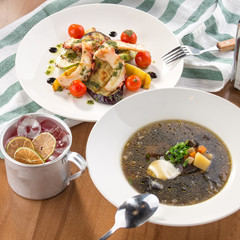 lunch set mushroom soup and grilled octopus with vegetables and iced cocktail on wooden table