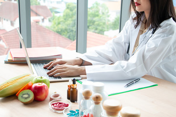 close up photo of Young Asian female nutritionist doctor work on laptop at wooden table with fresh...