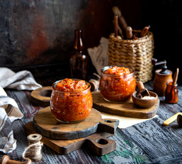 two glass jars with home made red vegetable caviar, ratatouille, ragout on wooden brown boards