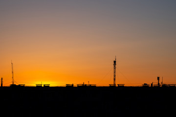 Obraz premium sunset city rooftops with antenna and lots of cables