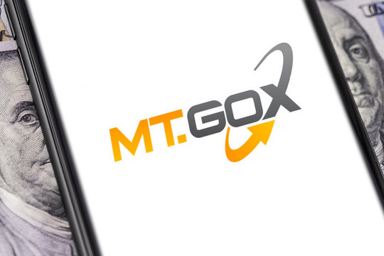 money, dollars and MT.GOX logo of exchange on the screen smartphone. MT.GOX is popular largest cryptocurrency exchange on the market. Moscow, Russia - March 26, 2019