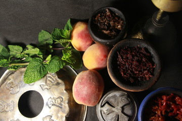 bowl with tobacco for hookah. red pomegranate on a black background. smoking nargile