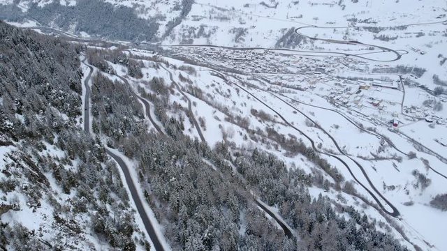 4K Mountain road with many curves cinematic aerial shot. Flying over a frozen landscape on a cold cloudy day
