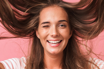 Image closeup of cheerful beautiful woman dressed in casual clothes smiling and having fun with flying hair