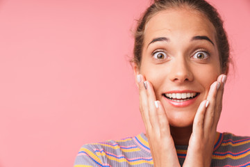 Image closeup of excited young woman dressed in colorful clothes smiling and touching her cheeks