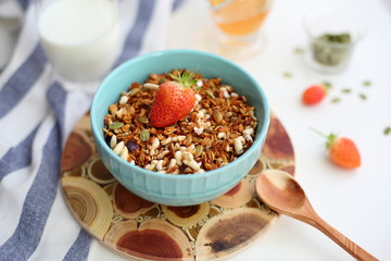 granola with strawberries in a plate on a white table