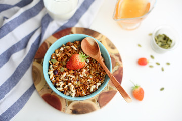 granola with strawberries in a plate on a white table