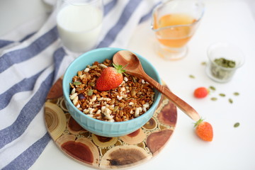 granola with strawberries in a plate on a white table
