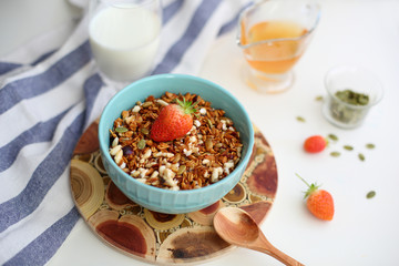 granola with strawberries in a plate on a white table