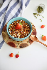 granola with strawberries in a plate on a white table