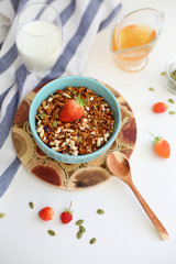 granola with strawberries in a plate on a white table