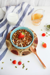 granola with strawberries in a plate on a white table