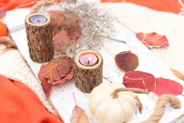 autumn still life. Colorful leaves, candle and white mini pumpkin on a light wooden tray. Selective soft focus.