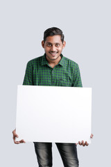 young indian guy holding blank poster