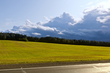 Thunderstorm front over a field and asphalt road in the sun