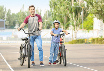 Obraz premium Happy father and son riding bicycles outdoors