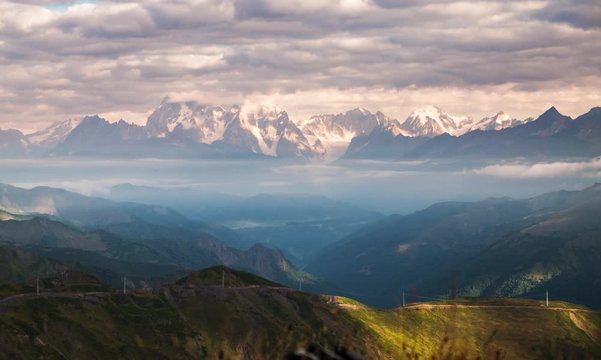 Landscape timelapse of sunrise in autumn mountains with rays of sun light and clouds with a road and power line on a mountain ridge