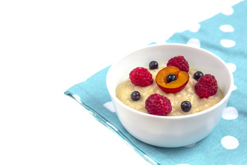 Healthy breakfast porridge for kids. Bowl of baby food on a fabric isolated on white. T