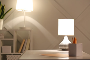 Workplace with glowing lamp in evening
