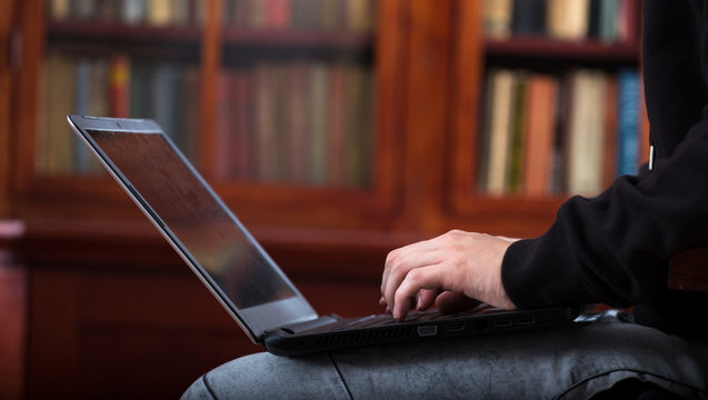 Student is working for exams on laptop in library