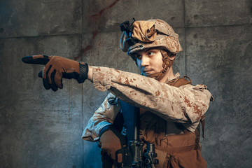Fototapeta premium fully equipped army soldier in camo uniform and helmet, armed with pistol and assault service rifle