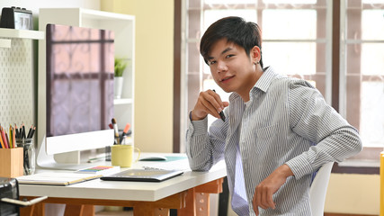 Asian man sitting on home office creative workspace.